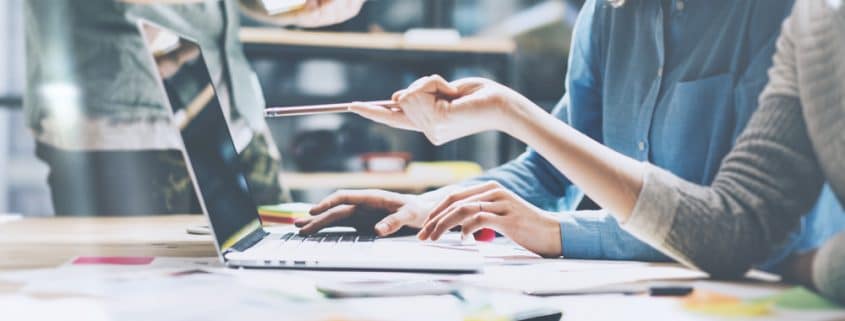 Two woman at a laptop discussing a project.