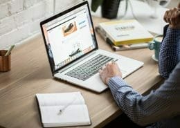 A man working on a laptop with a calendar beside him.