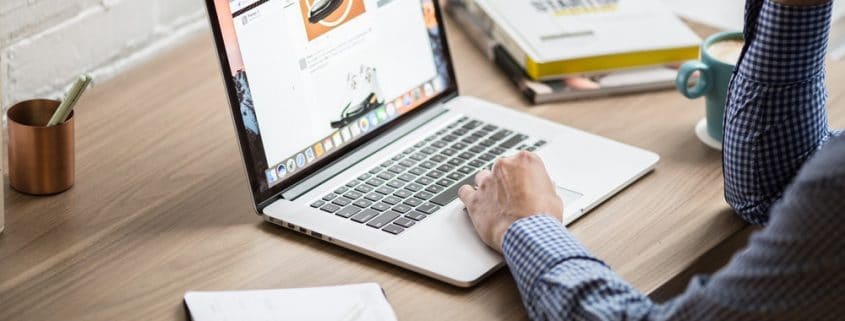 A man working on a laptop with a calendar beside him.