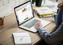 A man working on a laptop with a calendar beside him.