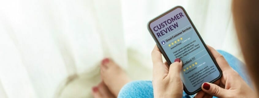 Person looking at cell phone displaying Customer Review