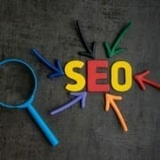 Colourful graphic with SEO letters surrounded by coloured arrows and magnifying glass
