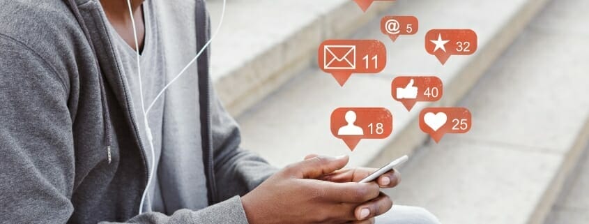 Man sitting on steps with cell phone plus a group of animate icons above showing what he has been doing on the phone