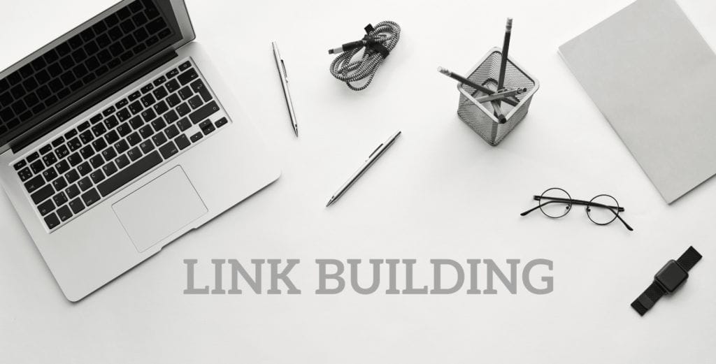 Laptop, pens, pencils, watch and eyeglasses with the words Link Building