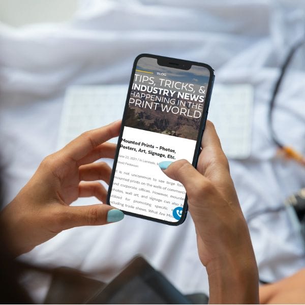 Female holding a cell phone with PRI Graphics site page displayed