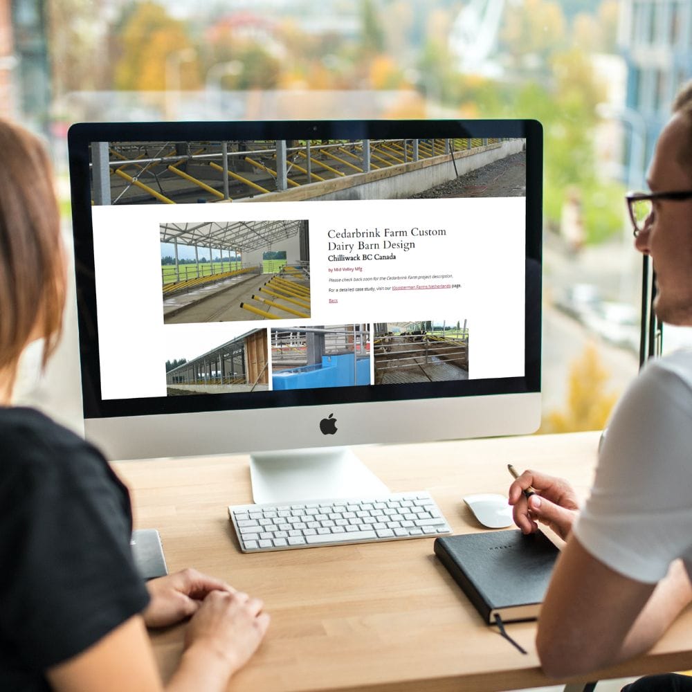 Two people working on a Mac desktop displaying Mid Valley Mfg website