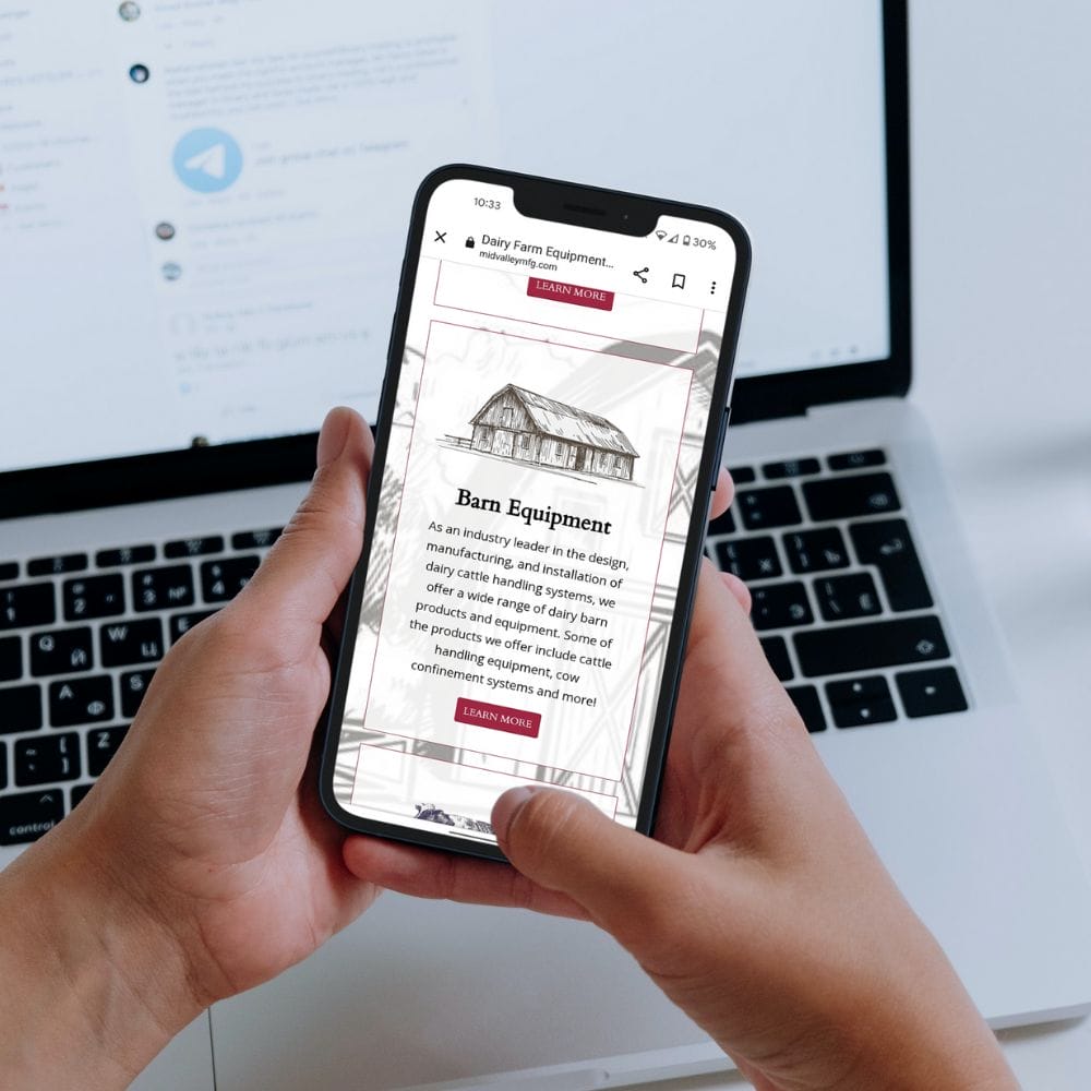 Hands holding a cellphone with image for Barn Equipment website