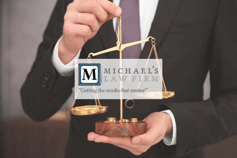Businessman holding the scales of justice with the Michael's Law Firm logo over the image