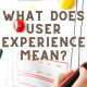 Person holding a smartphone and writing on a white board with the caption What Does User Experience Mean?
