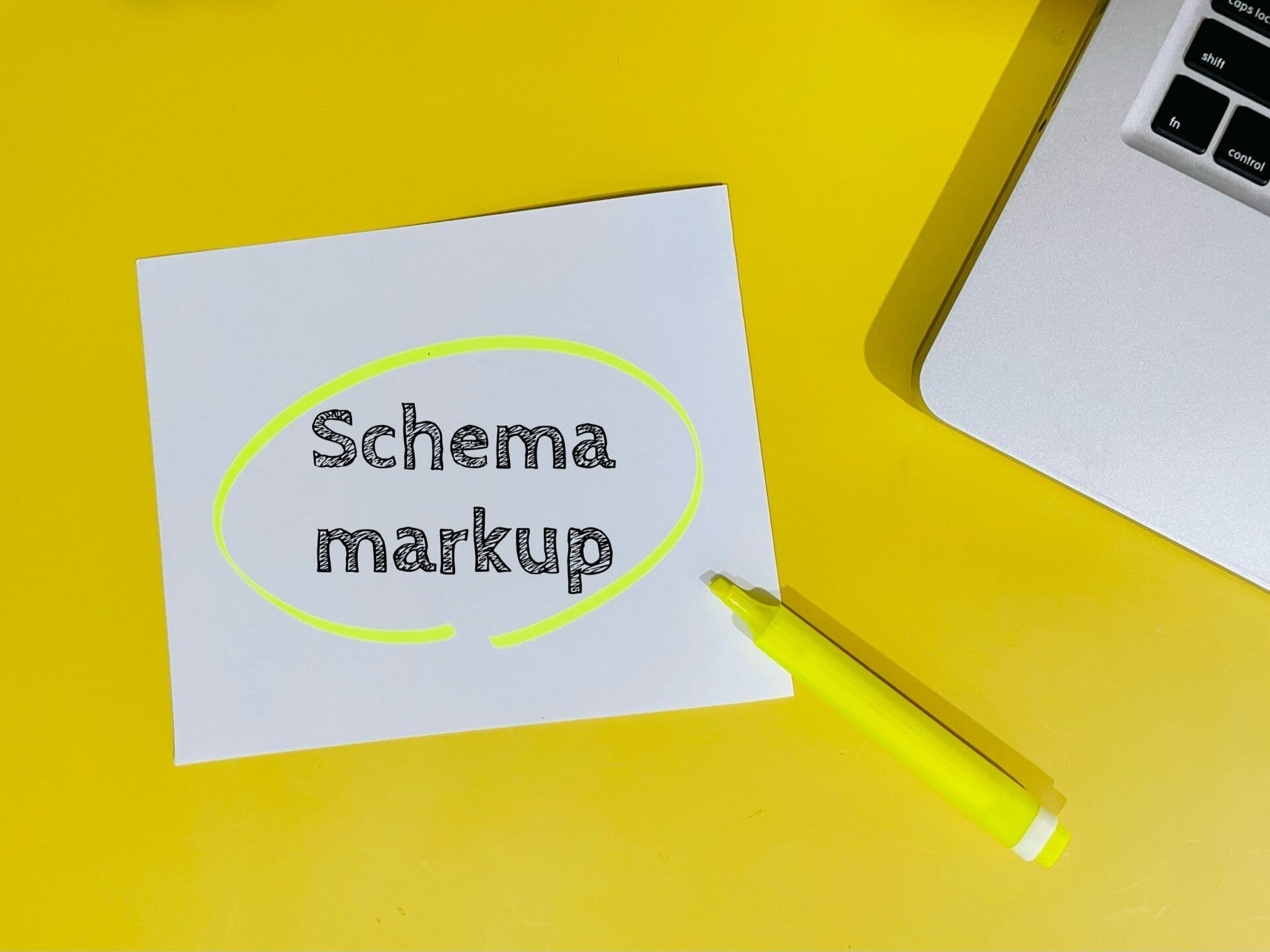 Paper with the words schema markup on a yellow desk