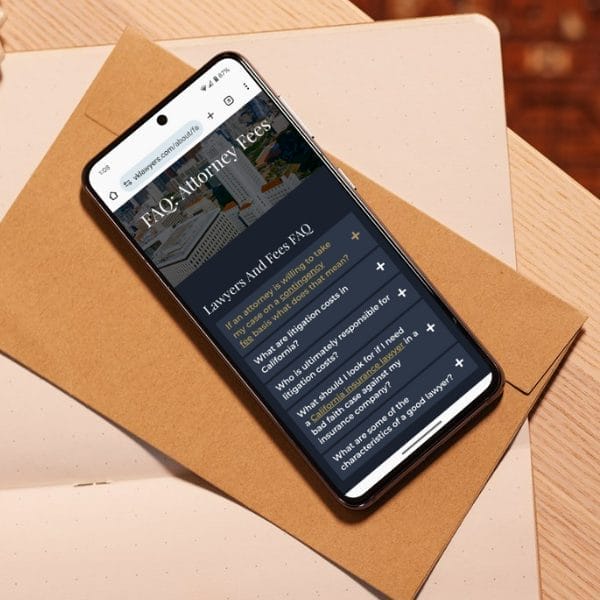 A smartphone displaying a webpage on "Lawyers and Fees FAQ" rests on a brown envelope placed on a wooden surface. The page lists questions related to attorney fees and responsibilities.
