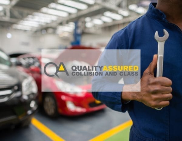 A person in a blue mechanic uniform holds a wrench in an auto repair shop. The background shows cars in various colors. A transparent overlay displays the text "Quality Assured Collision and Glass.