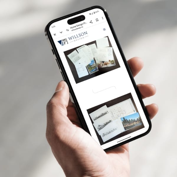 A person is holding a smartphone displaying architectural design plans on the screen, with the Willson Design logo visible at the top. The background is softly blurred, focusing on the phone and its content.