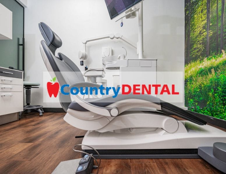 Modern dental office with a sleek white dental chair and equipment set against a backdrop featuring a forest scene. "Country DENTAL" is prominently displayed on the image, with an apple icon included in the design.