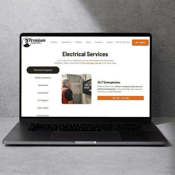 A laptop on a gray surface displaying a website for "Premium Electric." The screen shows sections such as Electrical Emergency, Safety Inspections, and Solar Panels. Buttons read "Get a Quote" and "24/7 Emergencies.