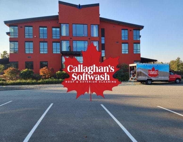 A red building with large windows stands behind a parking lot. In front, a truck for Callaghan’s Softwash Roof & Exterior Cleaning is parked, and a large red maple leaf logo with the company name is overlaid on the image.